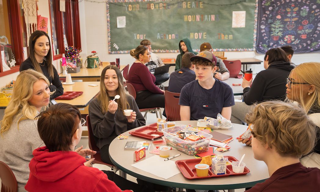 Social work intern Avery Burnsworth (far left) and Kristin Galusha (standing), a mental health site coordinator, with Whitney Point High School students during a BUCS lunchtime drop-in session this past February.