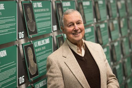 Gary L. Truce in front of the Binghamton University Athletics Hall of Fame wall in the Events Center.