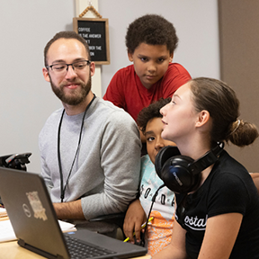 A young male teacher intereacts with students