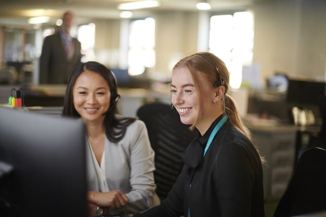 Two women looking at a computer screen smiling