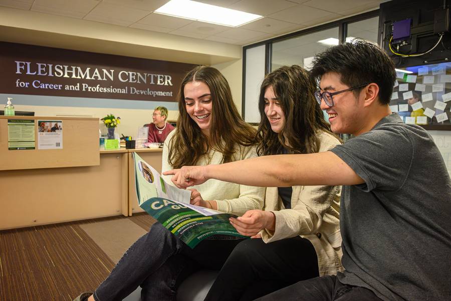 Three students reading the Career Guide in the Fleishman Career Center