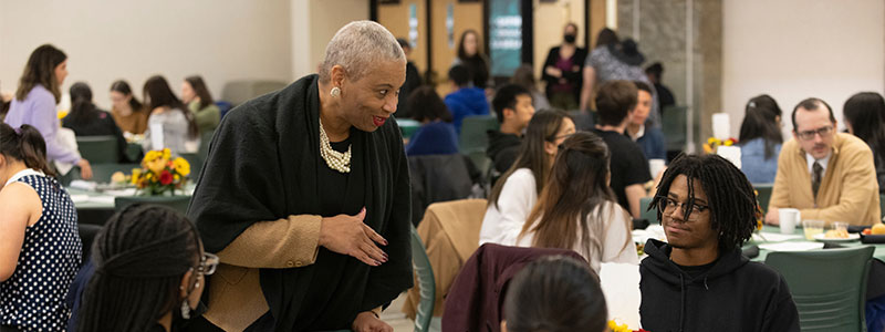 A faculty member talking with students at a table photo