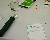 Table seating at the Career Champions breakfast that features a booklet, glass, and confetti.