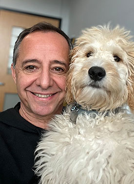 headshot image of serdar atav with his white fluffy dog