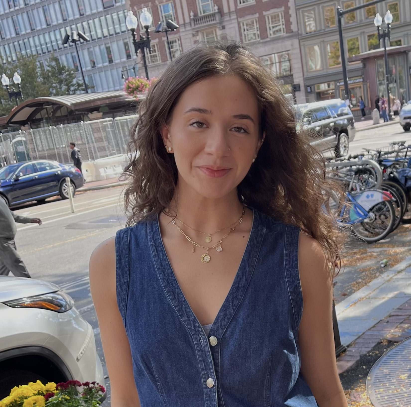 Portrait of person with long hair smiling in front of a parking lot.