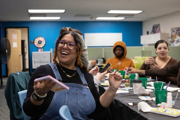 A young woman smiles while working on an art project