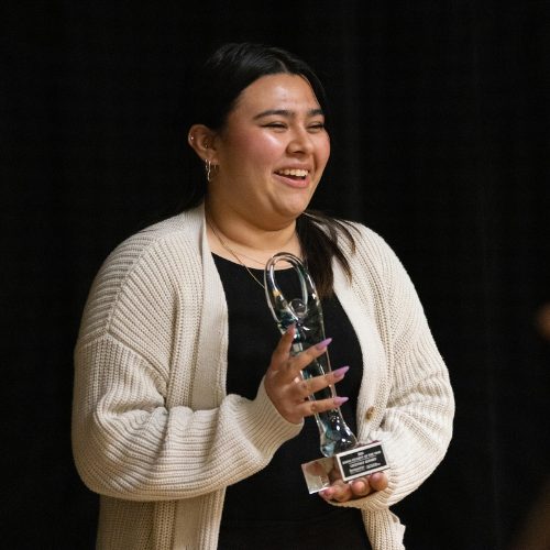 A young woman holding an award