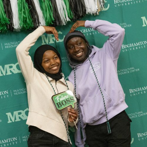 Two students pose in front of a banner