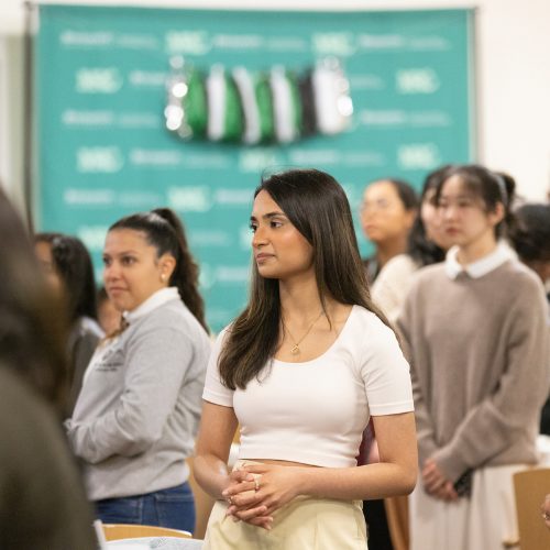 A young woman stands in the midst of a eated crowd