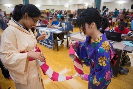 student helping another student with cultural attire at the MRC culture fair