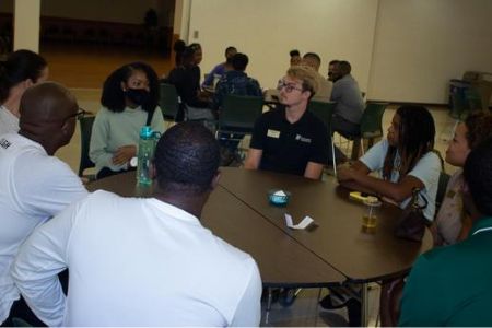 a group of students, faculty and staff engaging in dialogue at a round table at the fall 2022 new student of color networking event