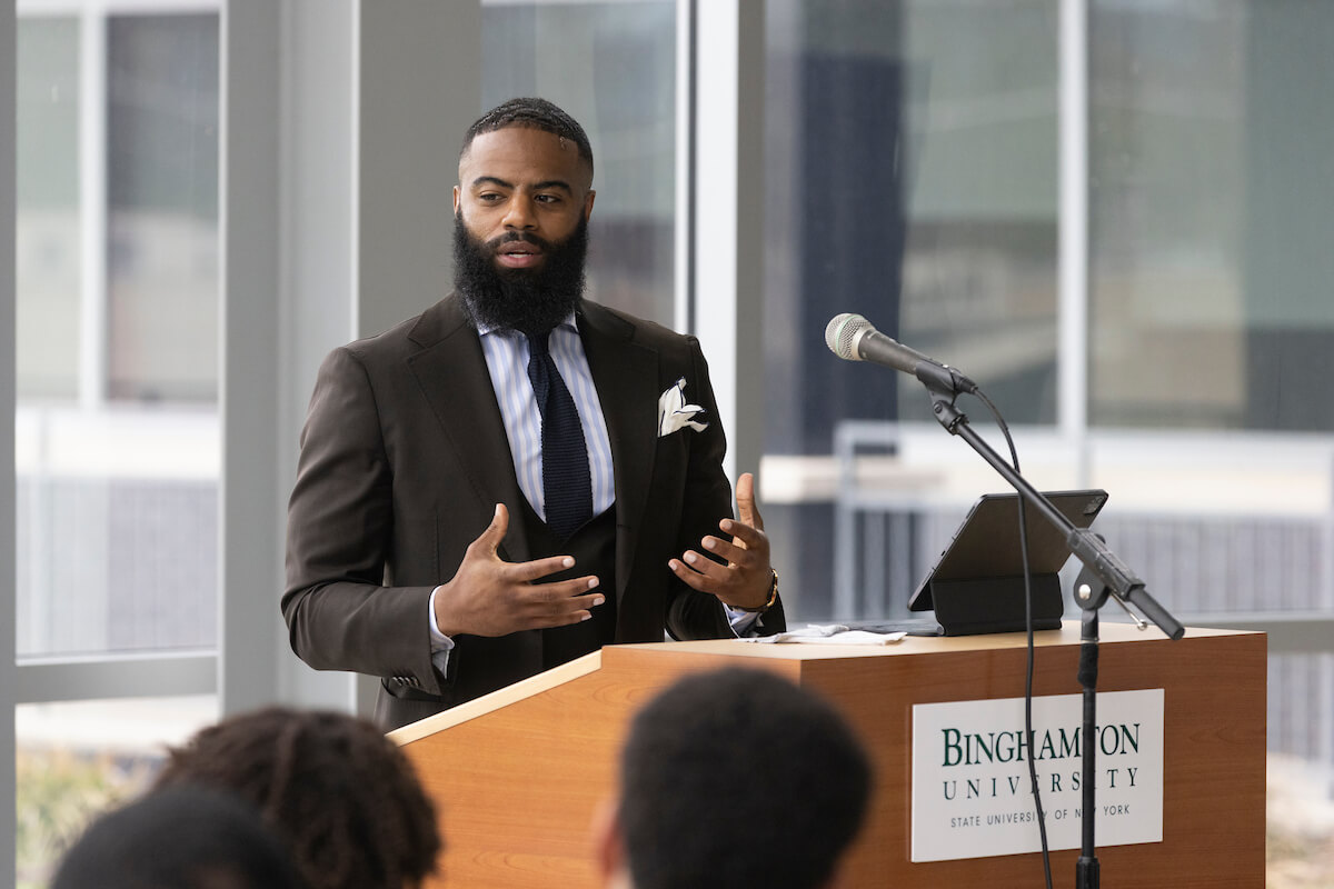 A Black man stands at the podium speaking to a crowd.