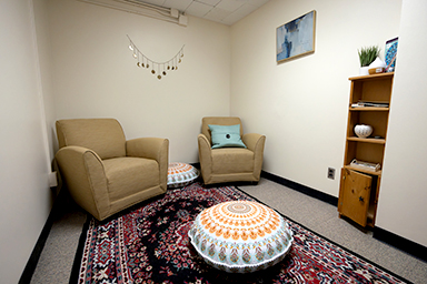 A small room with two chairs, and prayer mats
