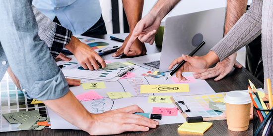 Staff around a table looking at their  ideas written out on stickies. photo