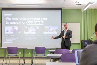 man in business suit getting doing presentation in front of screen