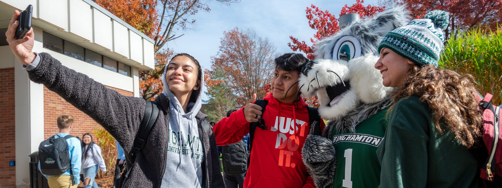 A group of diverse students pose with Baxter for a selfie.