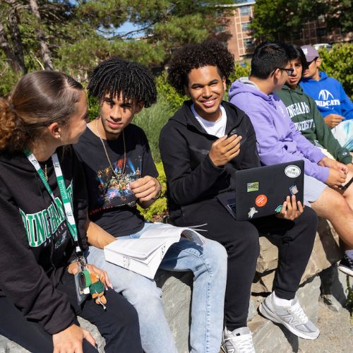 A group of young men sit on a wall outside