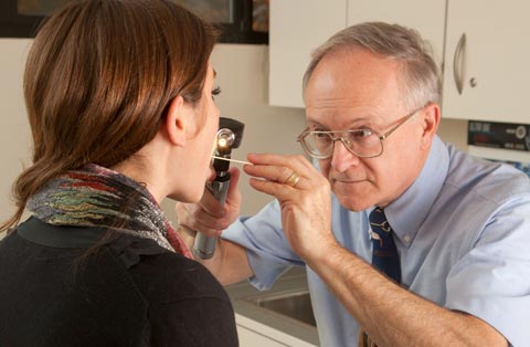 Male doctor examines female patient's throat photo