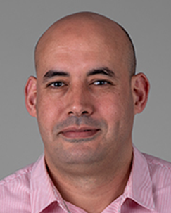 Photo of a man with a bald head and a pink collared shirt