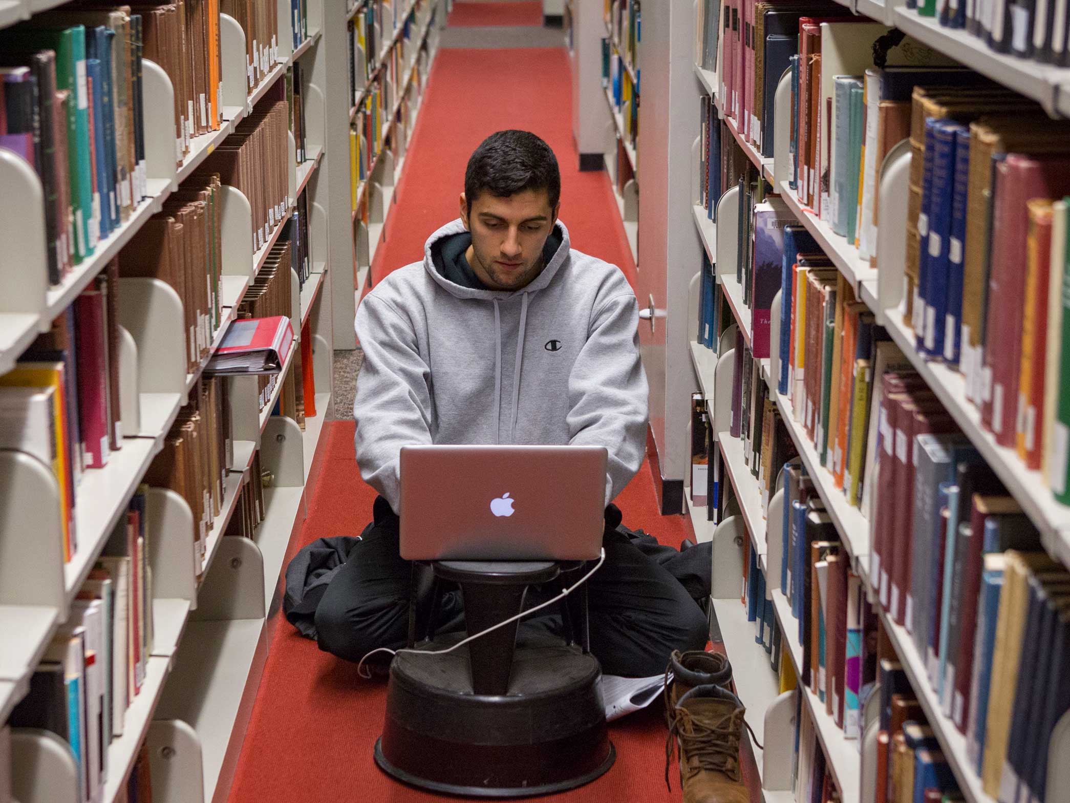 Student using a computer in library stacks