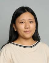Headshot of a young woman with dark brown hair wearing a white sweater