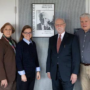 A group of people pose in front of a poster image of Fernand Braudel