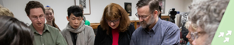 A Special Collections employee meets with faculty and students to show off a new acquisition