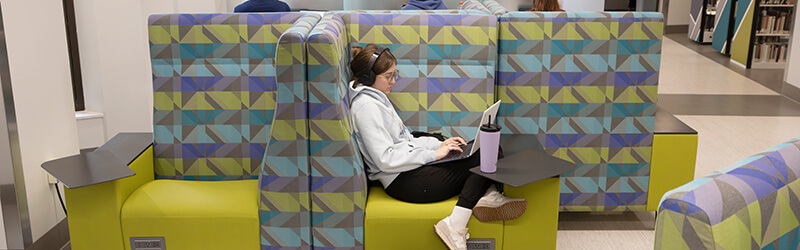 A student relaxes while studying on the cozy new seating on the third floor of Bartle Library