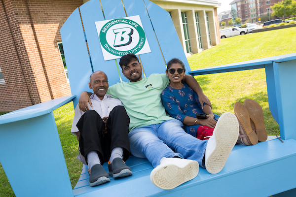 A family taking a photo in the big Adirondack chair during move in