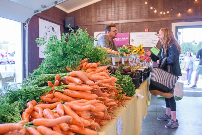 Man sells carrots and other fresh produce to woman