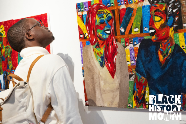 A young Black man looks at vivid abstract art.
