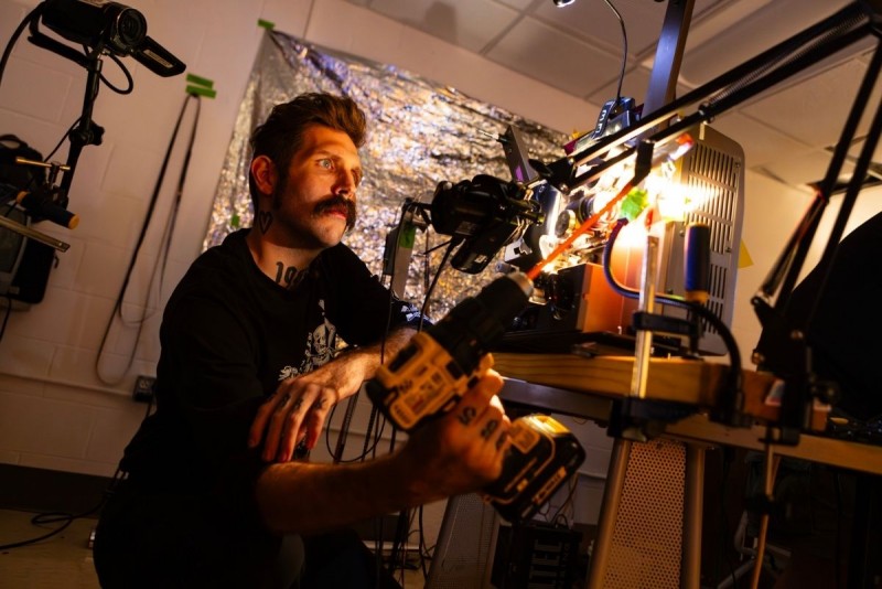 A student is shown operating a projector for an experimental, immersive cinematic experience.
