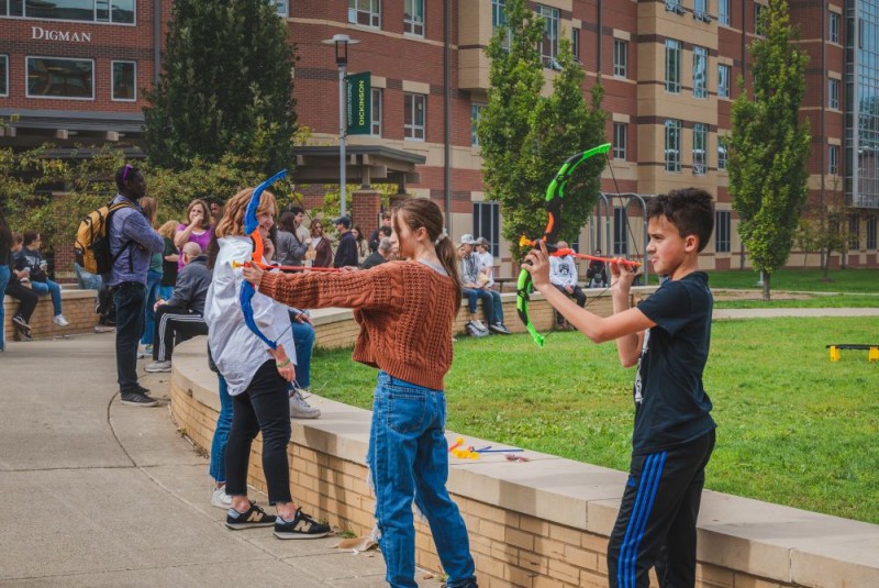 Students shoot suction darts at a target from plastic bows.