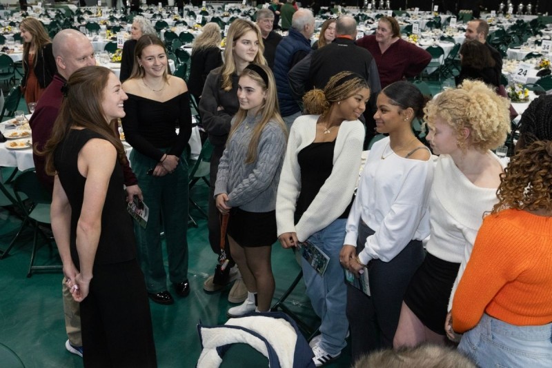 Alumna Emily Mackay stands with a group of students in the Events Center.