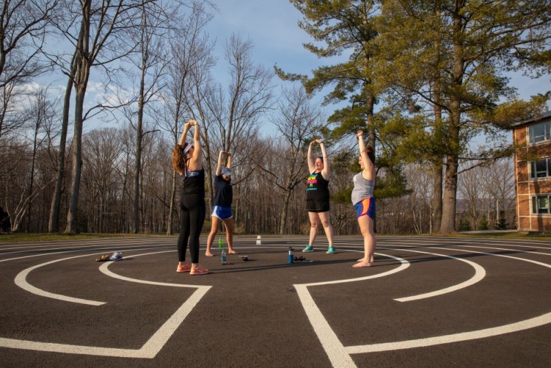 Four students stretch in a circle outside