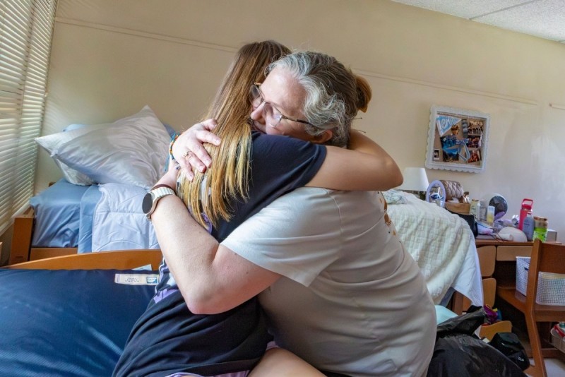 A student embraces their parent in their room during Move-in.