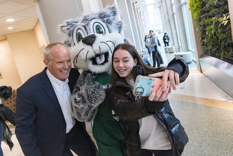 President Harvey Stenger takes a selfie with Baxter and a student.