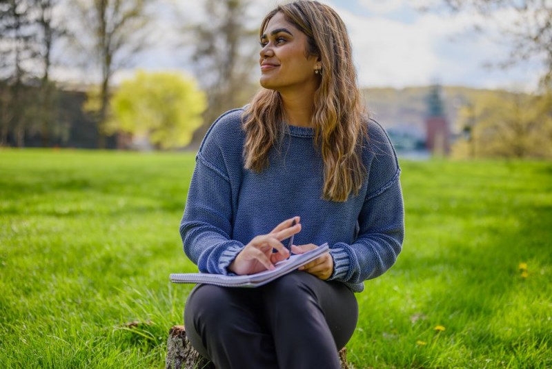 Smiling woman writing in a journal outside