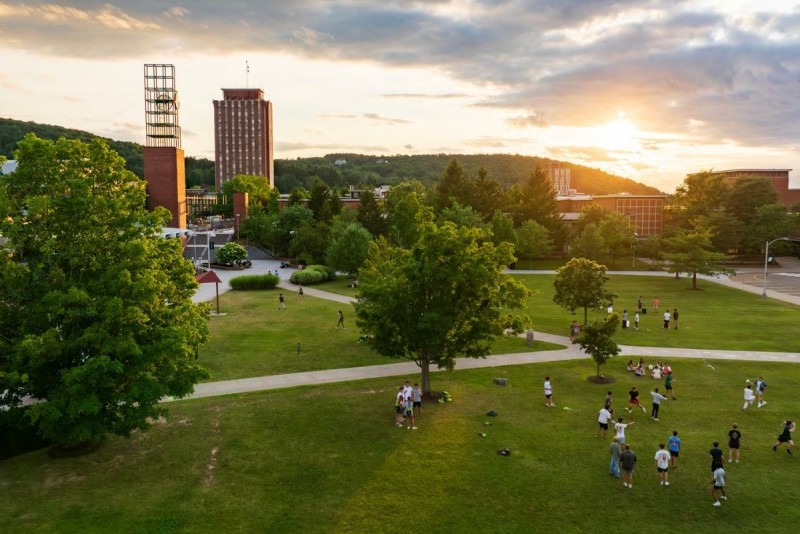 An aerial view of the Peace Quad shows a large group of students playing games during sunset.