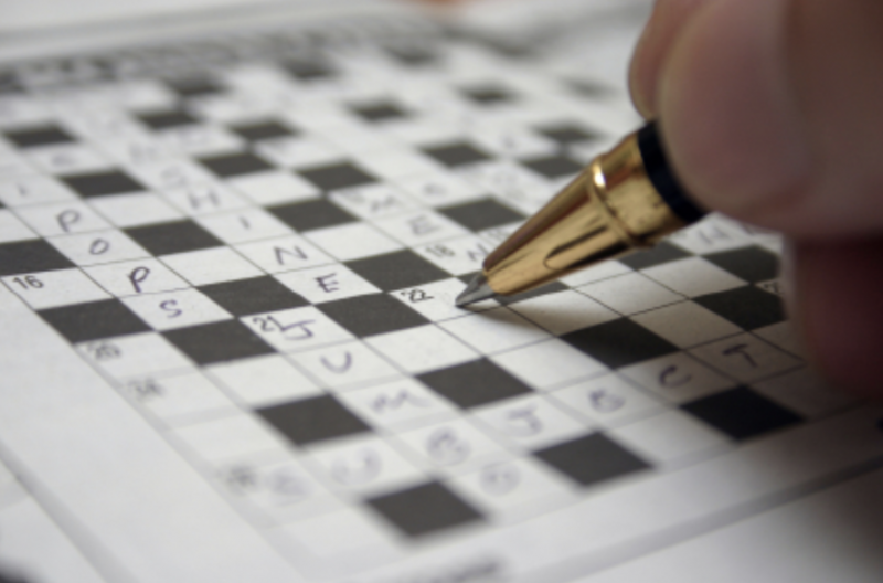 Photo of a pen filling out a crossword puzzle