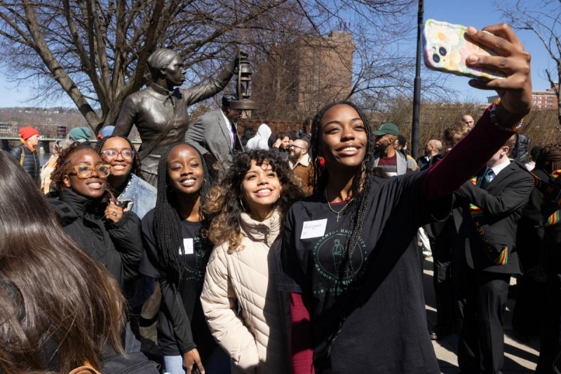 Several students take a selfie with a statue of Harriet Tubman.
