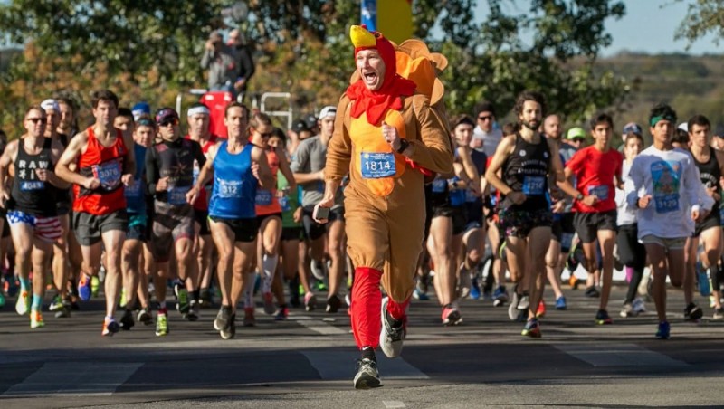 A man dressed as a Turkey leads a group of runners.