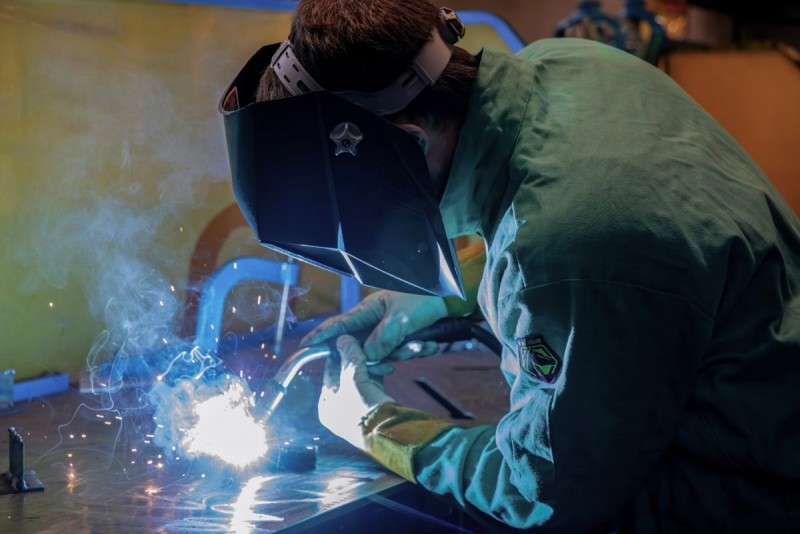 A person wearing a mask welds something in a lab.