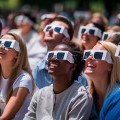 People view eclipse wearing protective glasses