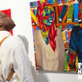 A young Black man looks at vivid abstract art.