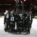 A hockey team huddles in the middle of the rink.