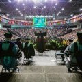 President Harvey Stenger is shown from behind on stage at Commencement with his arms raised in excitement.