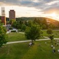 An aerial view of the Peace Quad shows a large group of students playing games during sunset.