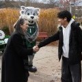 President Anne shakes the hand of a student outside on campus.