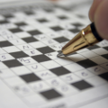 Photo of a pen filling out a crossword puzzle